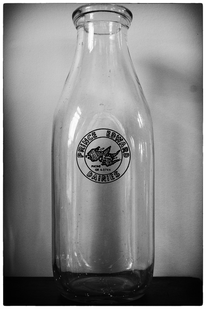 black and white photo of an old glass milk jug, with Prince Edward Dairies on the logo