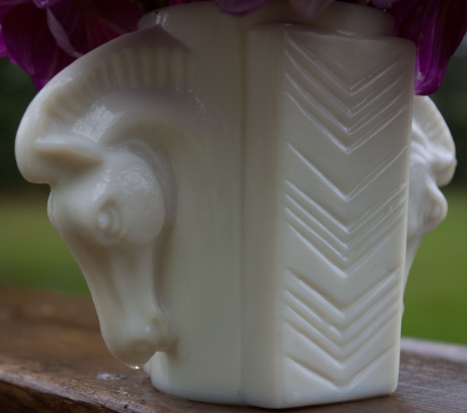 Close-up of art deco milk glass vase - a cup with two horse head handles